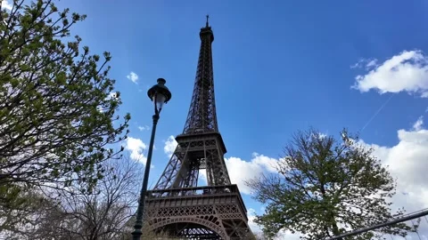 Wide Static Low Angle Shot of Eiffel Tower with Street Lamp and Spring Trees Vídeos de archivo 332602123