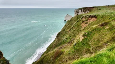 Wide static shot of the iconic cliffs and sea arch of Étretat under a cloudy sky Vídeos de archivo 332861939