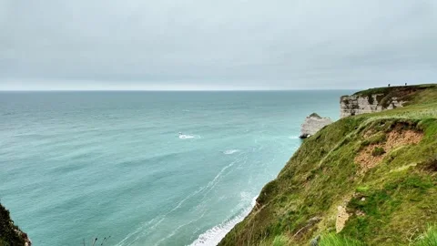 Wide static shot of the iconic cliffs and sea arch of Étretat under a cloudy sky Vídeos de archivo 332861982
