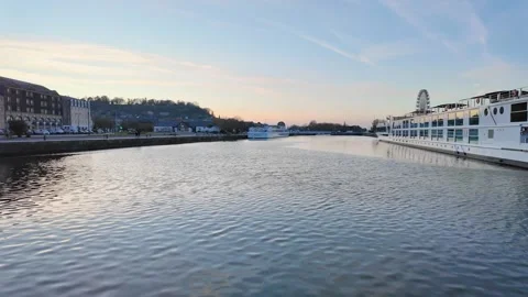 Wide static shot over calm river waters reflecting a pastel sunset and a moored Vídeos de archivo 332860910