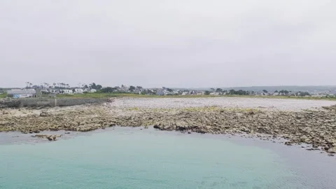 Wide static shot of the rocky coastline and clear turquoise waters at Pleumeur Stock Footage 346703331