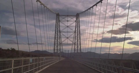 Wide Static Shot Sunset Suspension Bridge, Man Walks Into Frame Stock Footage 75784709