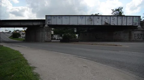 Wide static shot of a train bridge over the road with grafitti that says Cool 動画素材 50984881