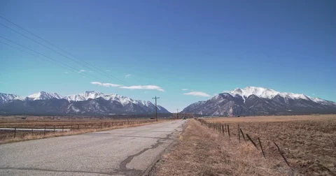 Wide Static Shots Of Long Road To Colorado Mountains, Car Drives By Stock Footage 75784454