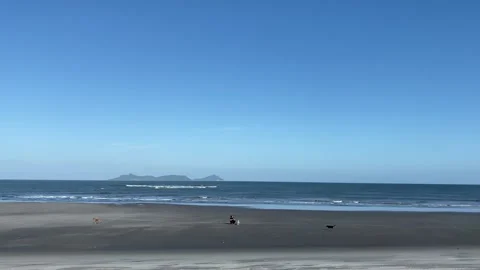 Wide sunny beach with dark sand and distant islands under blue sky Stock Footage 344977172