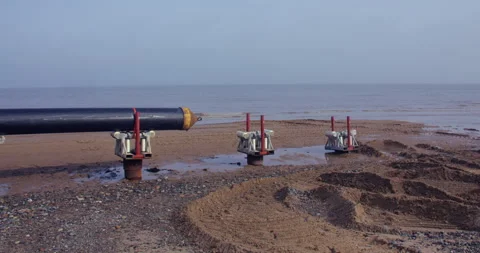 Wide time lapse shot of the tide coming in on to the black pipe at HyNet carbon Stock Footage 346109829