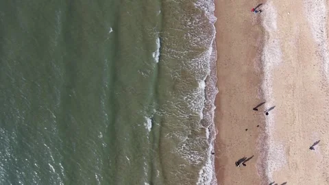 Wide Top Down Aerial View of People Walking beside Waves on Beach Stock Footage 344778371