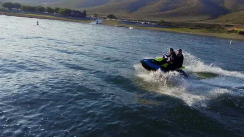 Wide tracking shot of two ladies riding one wave runner having fun Stock Footage 167803462