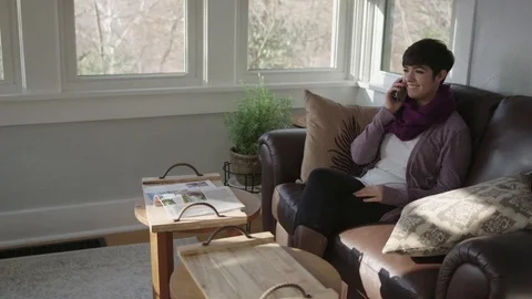 Wide tracking shot of young lady having a cordial conversation on her home phone Stock Footage 70809563