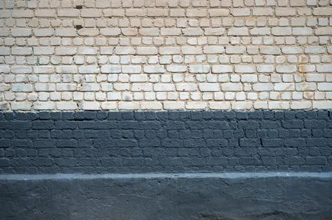 Wide urban brick wall texture with dark painted lower section 库存照片