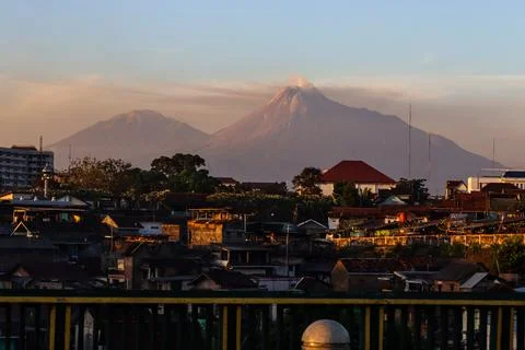 Wide View of Active Mount Merapi Volcano Above Dense City Houses at Sunset,.. Stock Photos