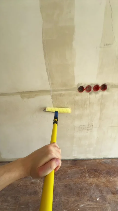 Wide view of applying wall primer with roller on extension pole Stock Footage 340405010