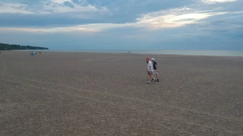 Wide view of the beach while in the middle ground three friends pass by 库存影片 113479103