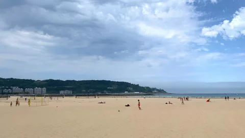 Wide view of beachgoers on the wide sandy expanse of Hendaye beach Stock Footage 345145772