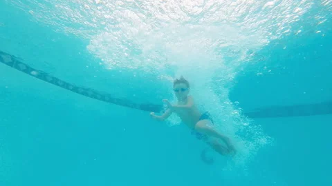 Wide view of boy jumping in deep end of swimming pool, waving, swimming off 스톡 동영상 248080710