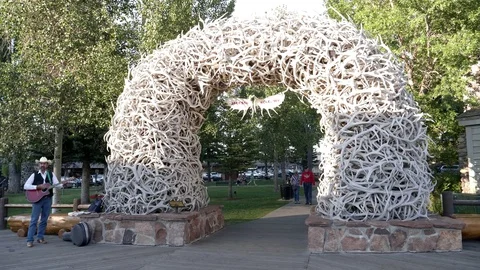 Wide view of a busker standing beside an antler arch in jackson hole, wyoming Stock Footage 84044969