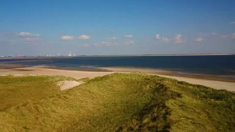 Wide view of coastline with sand dunes, beach, and water under blue sky in .. Stock Footage 339940682
