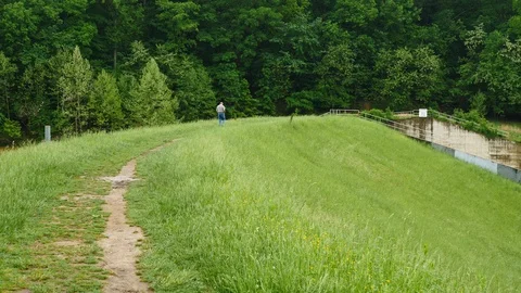 Wide View Elderly man walking along a green footpath Stock Footage 90078361