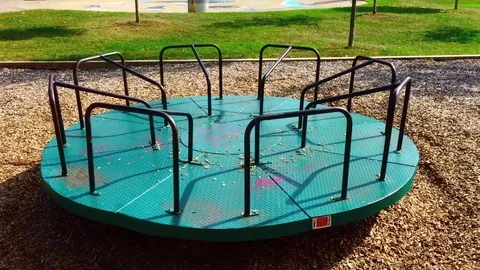 Wide view of empty Children's merry-go-round turning in a park Stock Footage 124318000