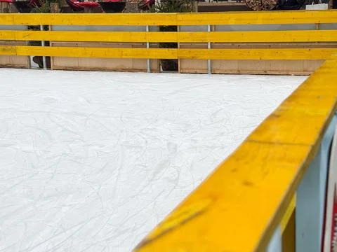 Wide view of an empty ice skating rink with wooden fencing. Winter recreation Foto stock
