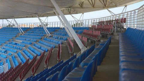 Wide View of Empty Stadium Seating With Blue and Red Chairs Under Curved Roof 動画素材 346654124