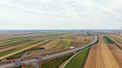 Wide view of fields and roads with wind turbines in the distance during daytime Stock Footage 342787579