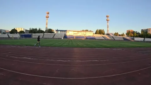 Wide view of full athletic stadium with green natural grass field man jogging Stock Footage 319792147