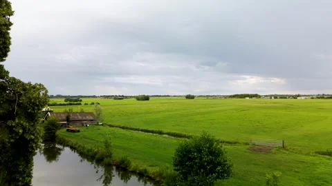 Wide view of green fields and meadows with a small canal, rural houses Stock Footage 316672045