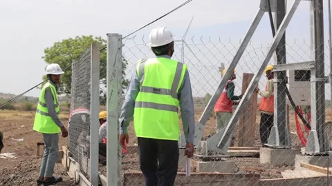 Wide view of industrial workers constructing a security fence at a new wind Stock Footage 337205758