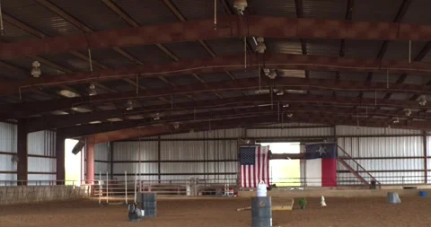 Wide view inside a spacious Texas equestrian arena with metal beams, dirt Video stock 345804489