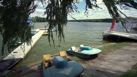 Wide view of iron boats moored on the shore of a lake. Slow motion. Stockbeeldmateriaal 123712740