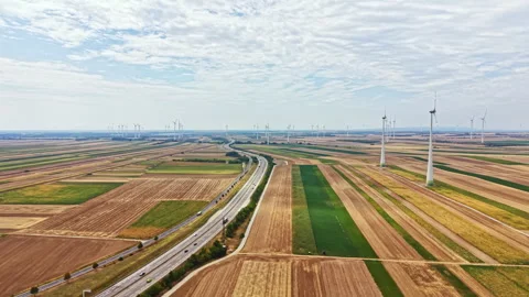 Wide view of a landscape with fields, a road, and wind turbines in the distance Stock Footage 342784837