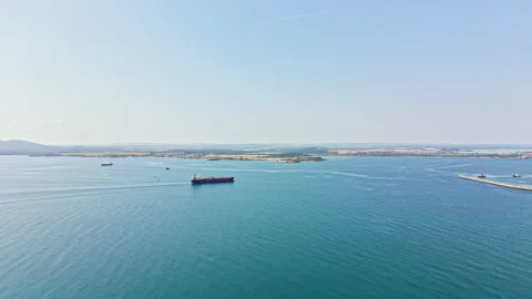 Wide view of a large ship moving through blue water near land during a clear day Stock Footage 340940725