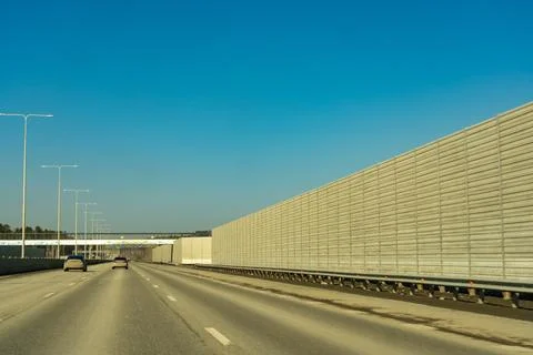 A Wide View of a Modern Highway Surrounded by Sound Barriers Under a Clear Bl Stock Photos
