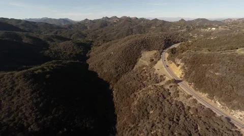 A wide view of the mountains. Flying over the hills overlooking the road Stock Footage 49878692