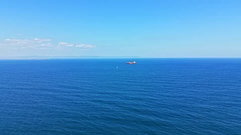 Wide view of ocean with a distant ship sailing under clear blue sky during Stock Footage 344809469