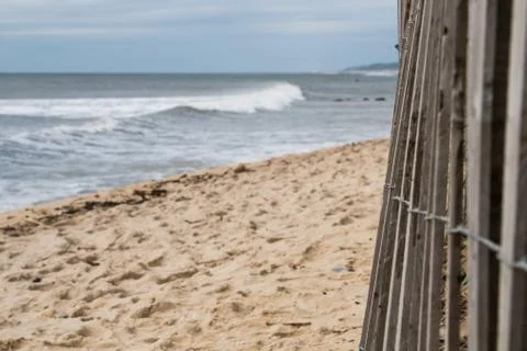 Wide view of an ocean front beach along the coast line past a wood fence Stock Photos