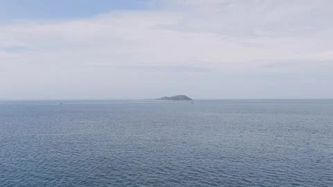 A wide view of the open sea with a distant island under a partly cloudy sky Stock Footage 346667013