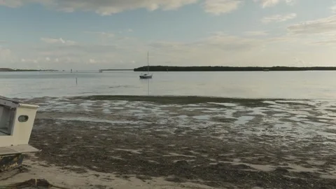 Wide view out over low tide puddles towards sailboat at Maximo Park water toward Stock Footage 284730814
