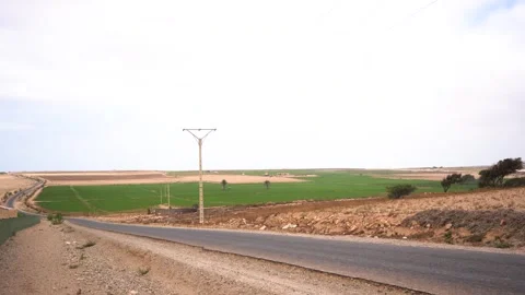 Wide View of Paved Road Overlooking Lush Green Farm Fields in Arid Morocco Vídeos de archivo 334180943