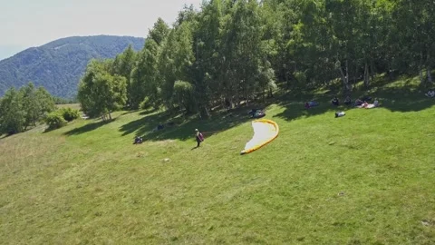 Wide view of people preparing chute for paragliding. Drone orbiting as Video stock 253617180