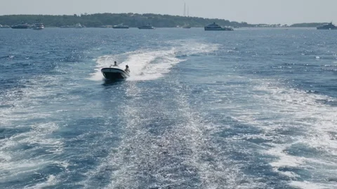 Wide view of people speeding in a rigid inflatable boat past anchored yachts Stockbeeldmateriaal 344811341