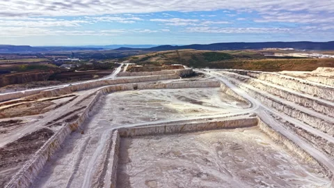 Wide view of a quarry site with steep walls and machinery at work in the Stock Footage 345455296