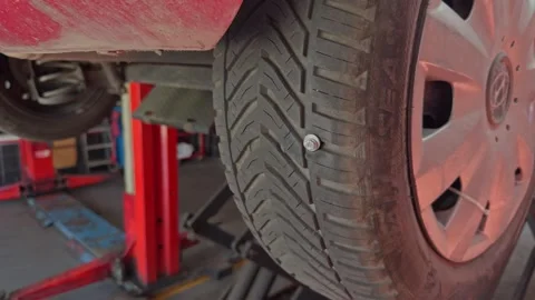 Wide View of Red Car Front Wheel with Screw in Tire Tread Stock Footage 344015578