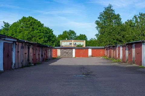 Wide View of Red Garage Complex in Sunny Asphalt Courtyard with Green Trees Stockfoto's