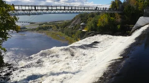 Wide view reveals a long bridge above the Montmorency Falls in Quebec City Stock Footage 62415679
