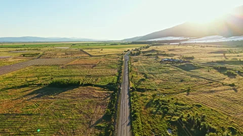 Wide view of a road running through fields and farmland during sunset with hills Stock Footage 341133594