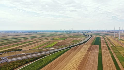 Wide view of a rural landscape with fields, roads, and wind turbines on a cloudy Stock Footage 342790120