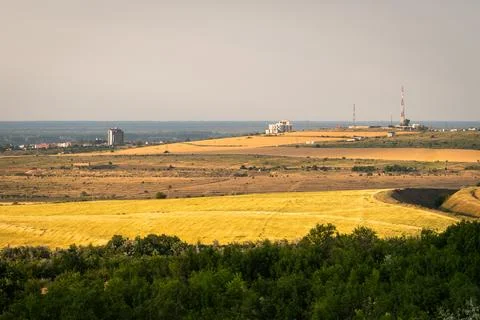 Wide view of a rural landscape with fields and distant buildings during day.. Stock Photos