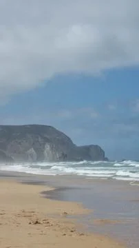 Wide view of a sandy Atlantic beach framed by coastal dunes and beach umbrell 库存照片